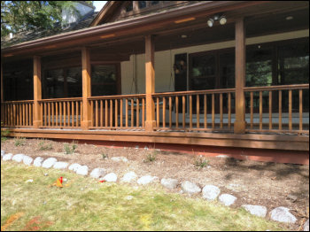 View of Home With Deck Extending From Tilted Basement Wall
